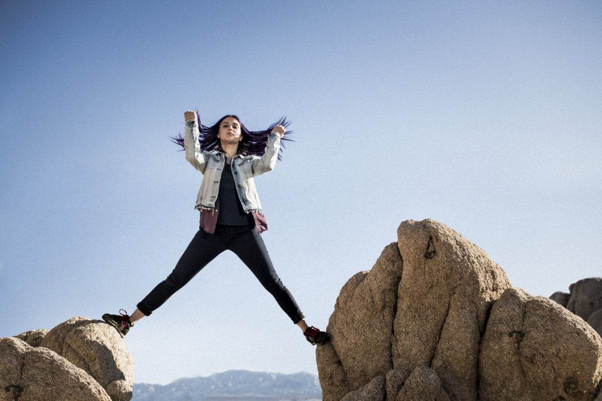 A woman standing atop large rocks — part of a campaign supporting REI's brand positioning strategy